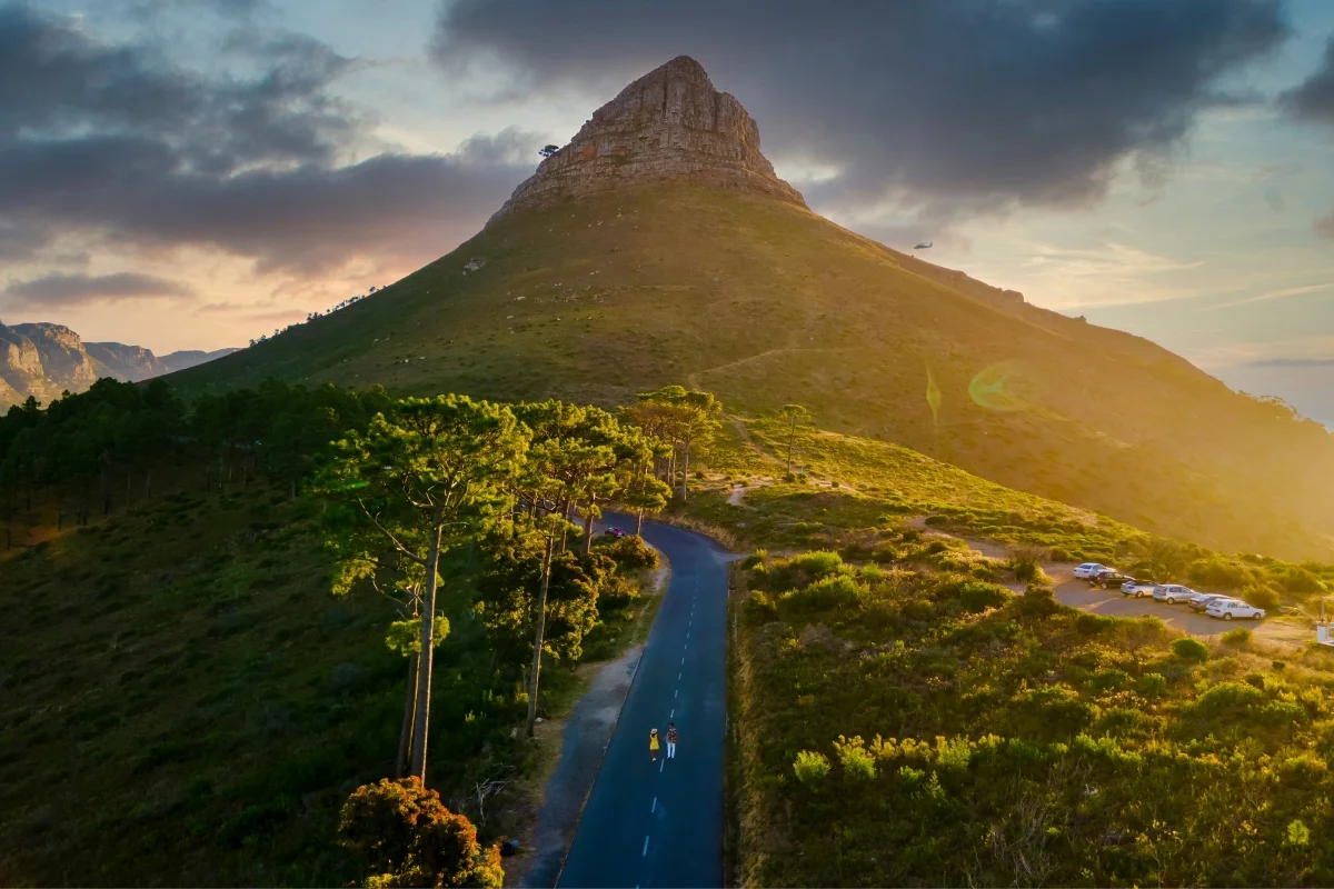 A scenic view of Lion's Head, with hikers on the trail and Table Mountain in the background