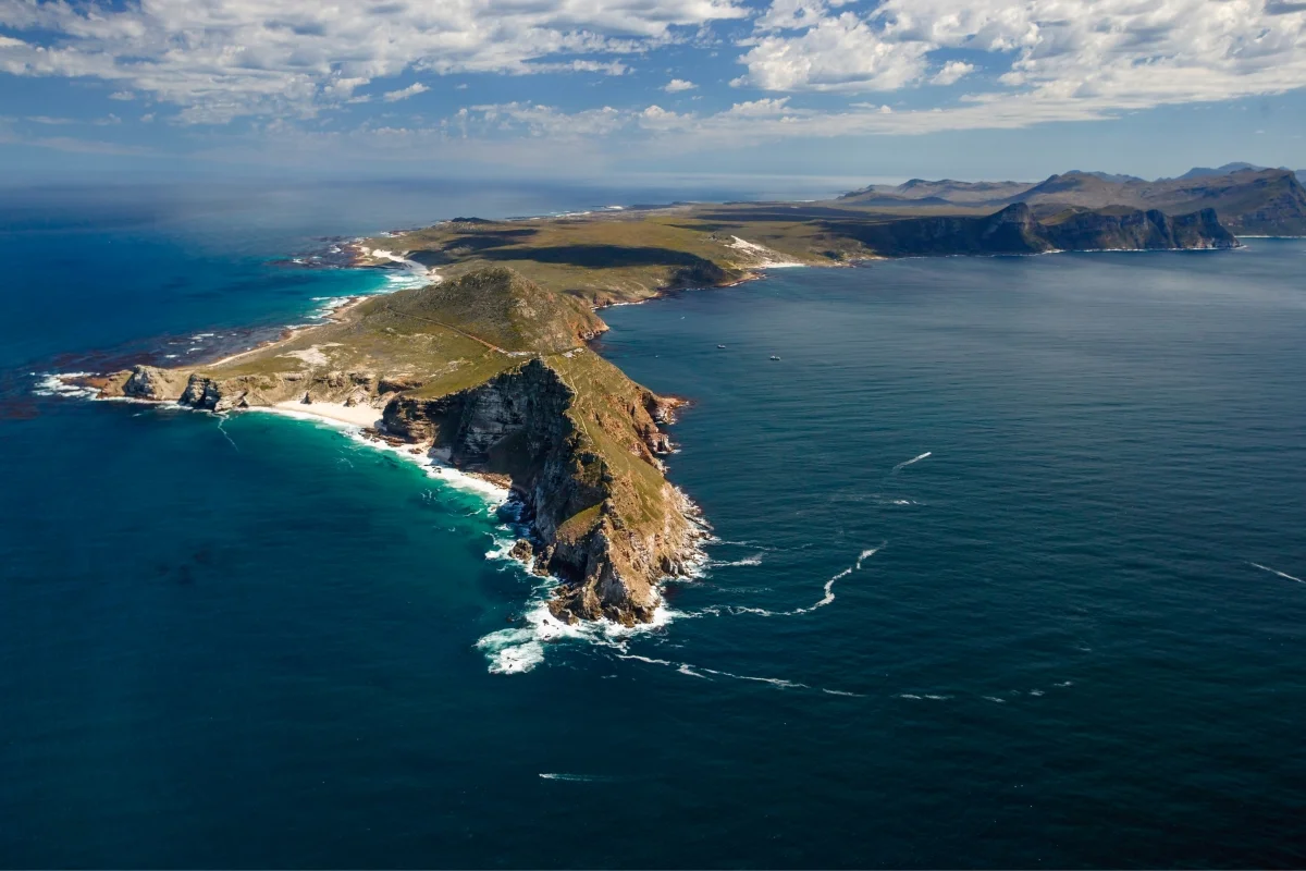 Aerial view of Cape Point, South Africa, showing the rugged coastline, cliffs, and the meeting point of the Atlantic and Indian Oceans