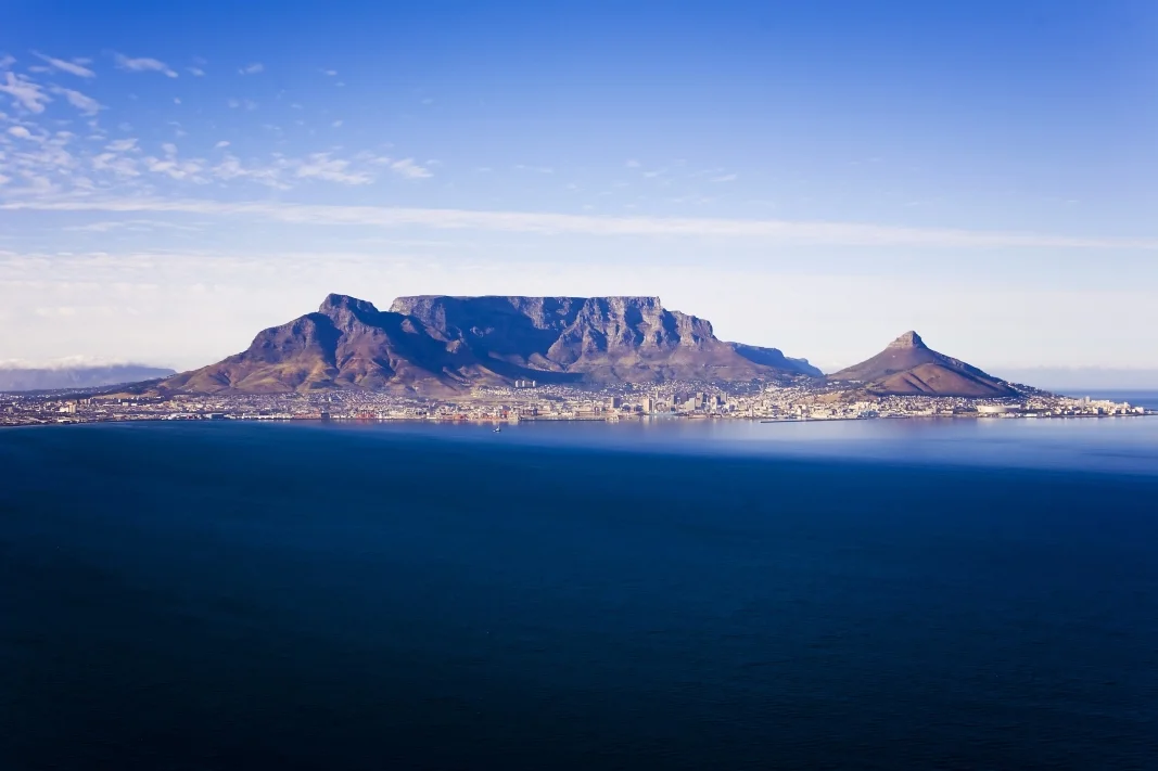 The iconic flat-topped Table Mountain dominates the skyline of Cape Town, as seen from the ocean