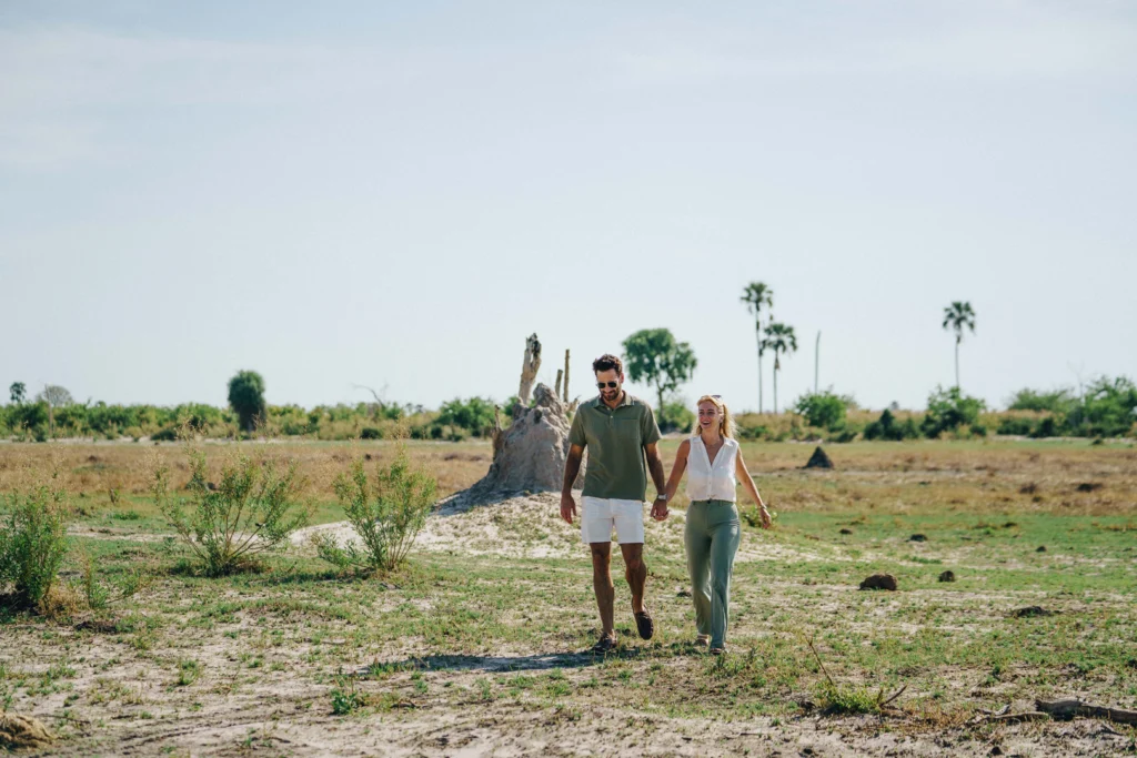 a couple walk holding hands through a vast African plain.