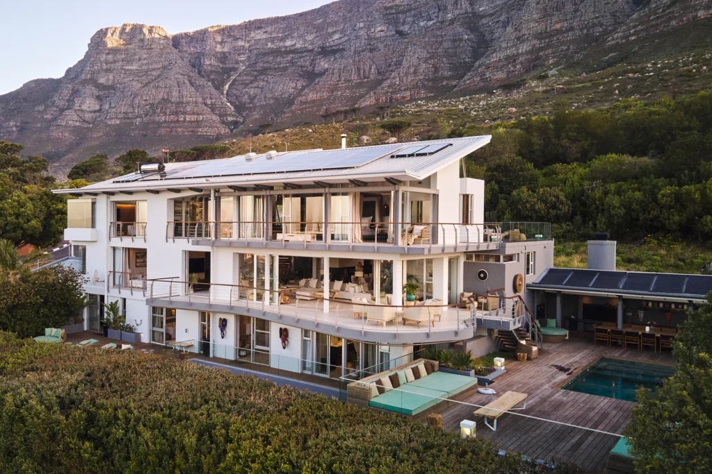The elegant exterior of Atzaró Cape Town with lush landscaping, stylish architecture, and Table Mountain rising majestically in the background.