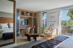 Interior of the Mopane Bedroom in the Atzaró Cape Town Family Suite, highlighting the work desk area, African wall art, large mirror, and sliding doors opening to the terrace.