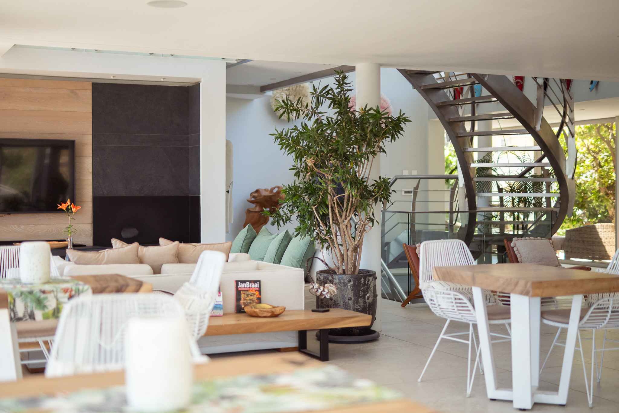 Open main area with TV lounge, dining tables, sofas, and staircase at Atzaró Cape Town hotel.