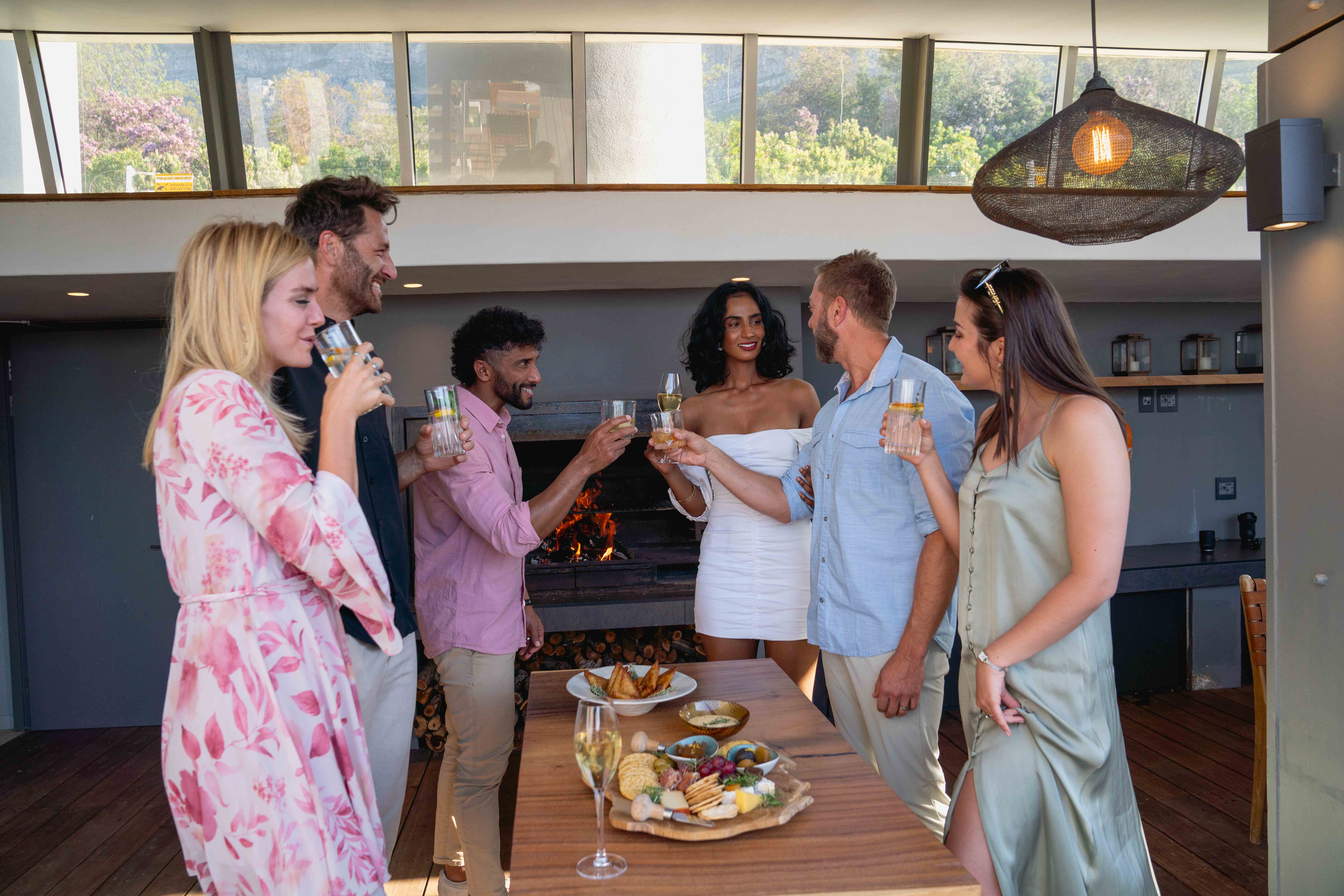 Friends toasting with drinks and appetizers during an elegant evening social gathering at Atzaró Cape Town boutique hotel.