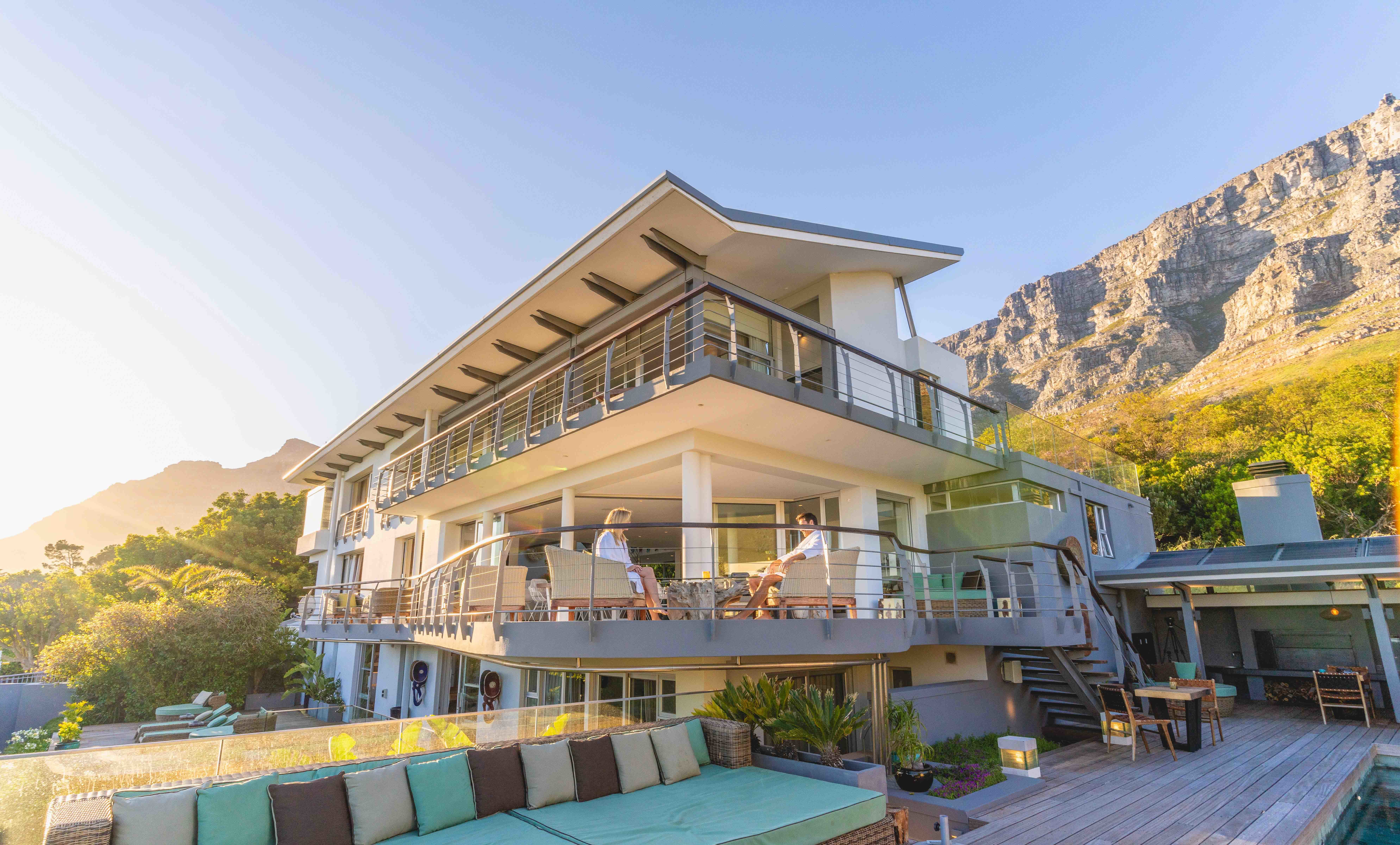 Panoramic view of Atzaró Cape Town boutique hotel architecture, featuring a sun-drenched outdoor terrace, swimming pool, and stunning mountain backdrop.
