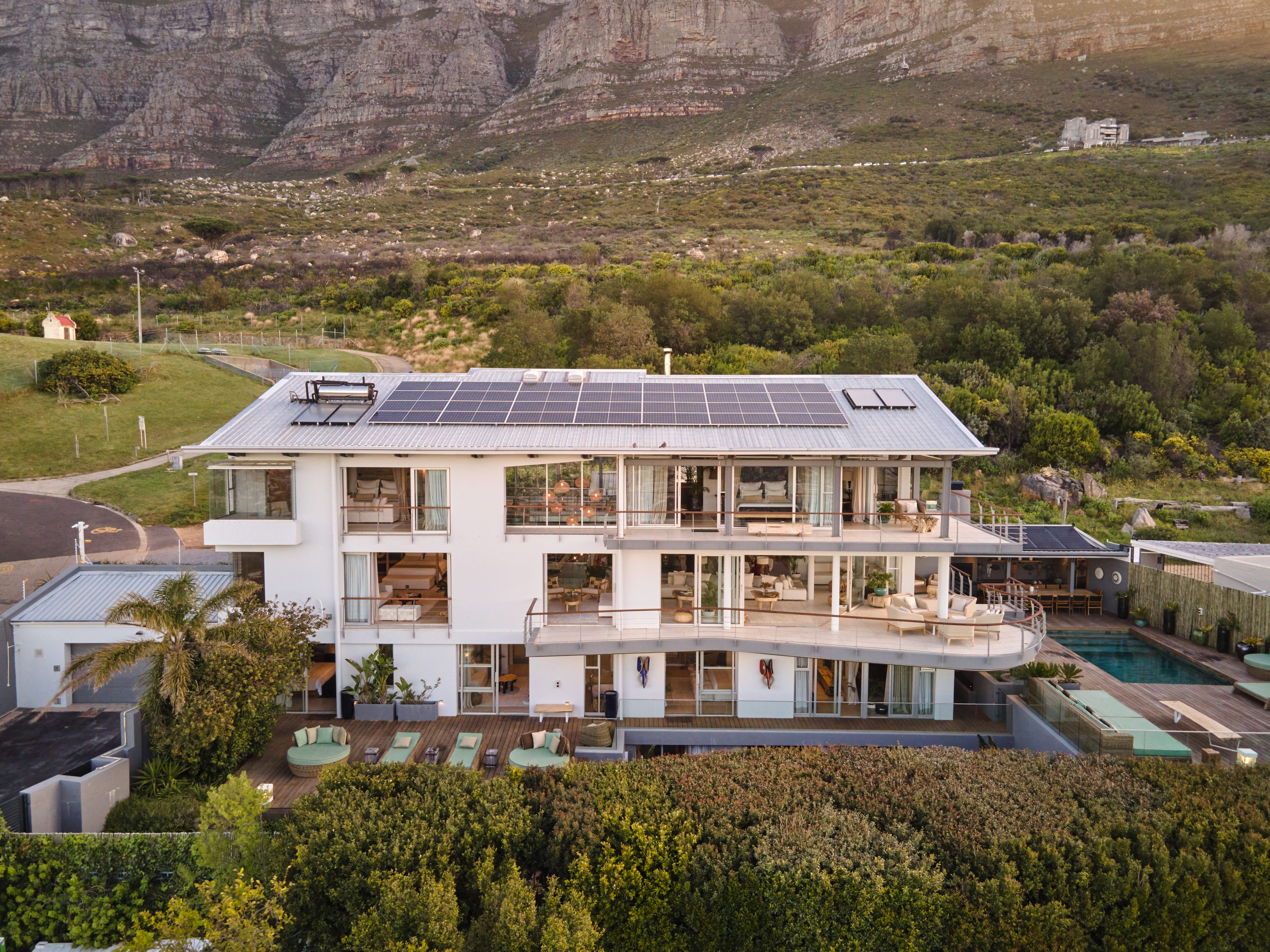 Luxury modern villa at Atzaró Cape Town illuminated at dusk with the iconic Lion's Head mountain in the background.