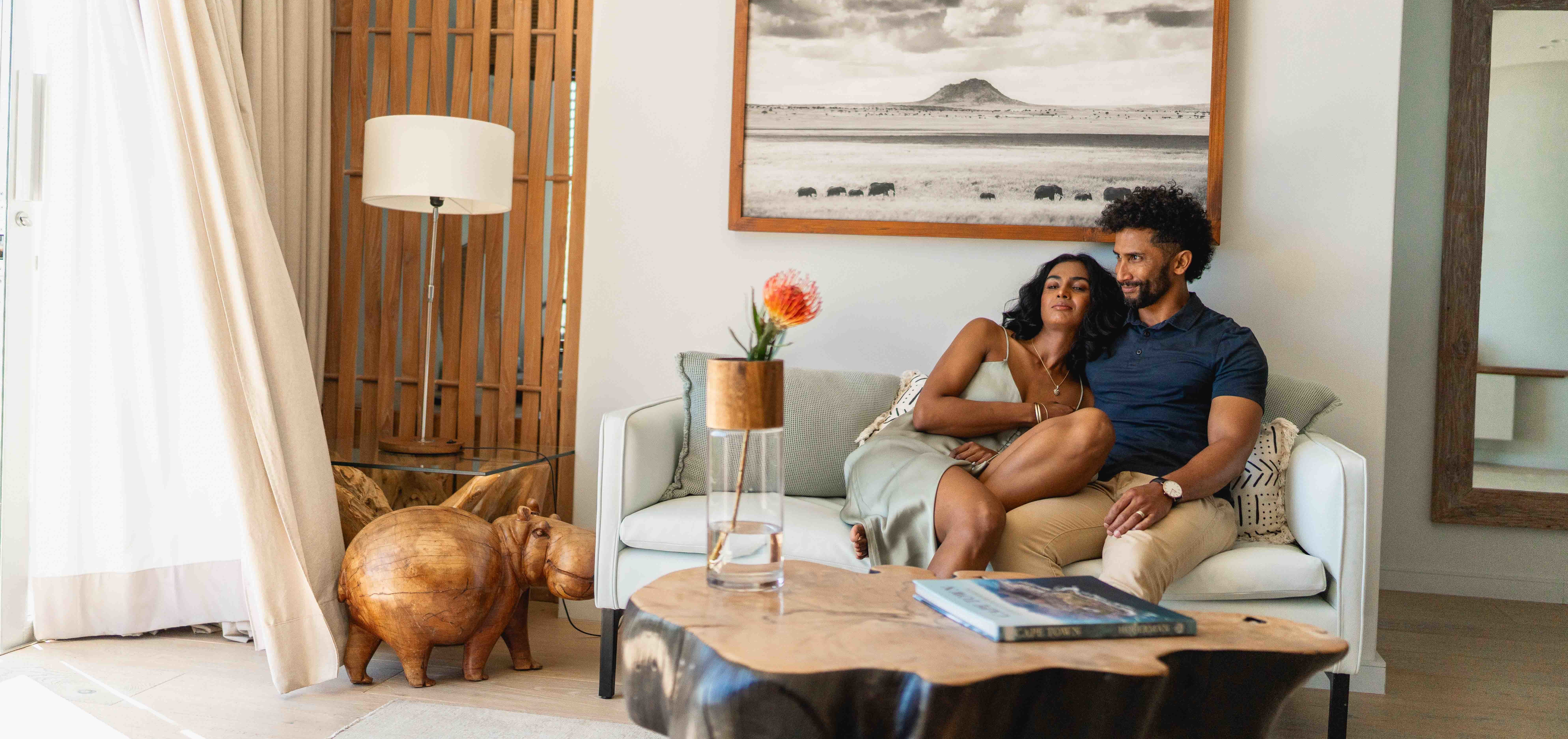 A couple relaxing on a sofa in their suit in Atzaró Cape Town Small Boutique Hotel.