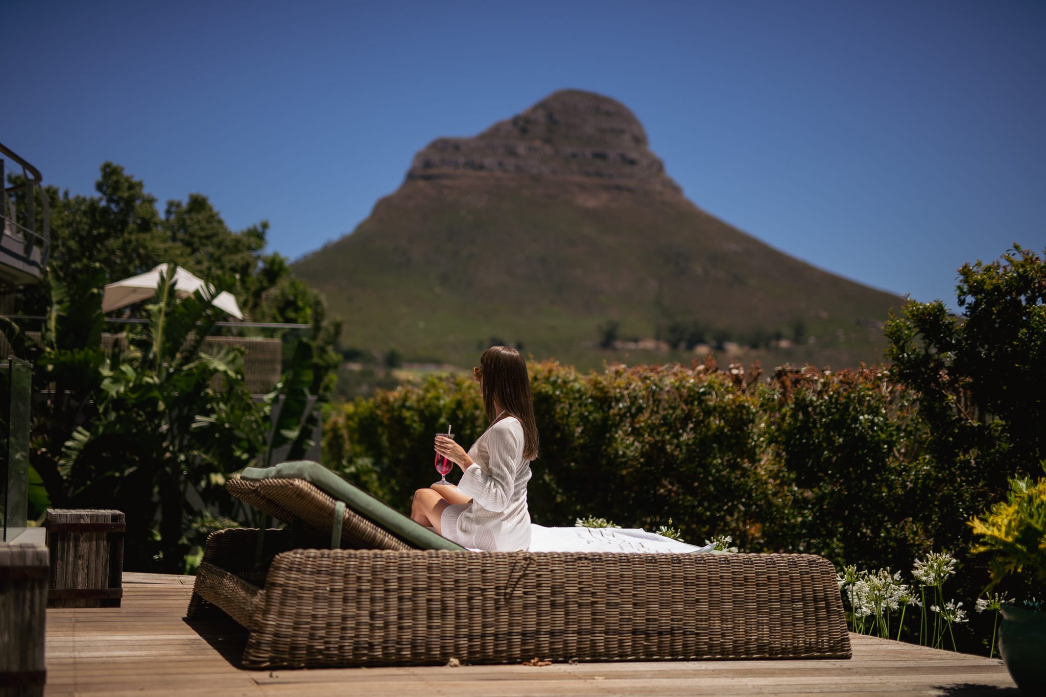 Woman drinking a cocktail on a terrace in Atzaró Cape Town in front of the Lion's Head Mountain.