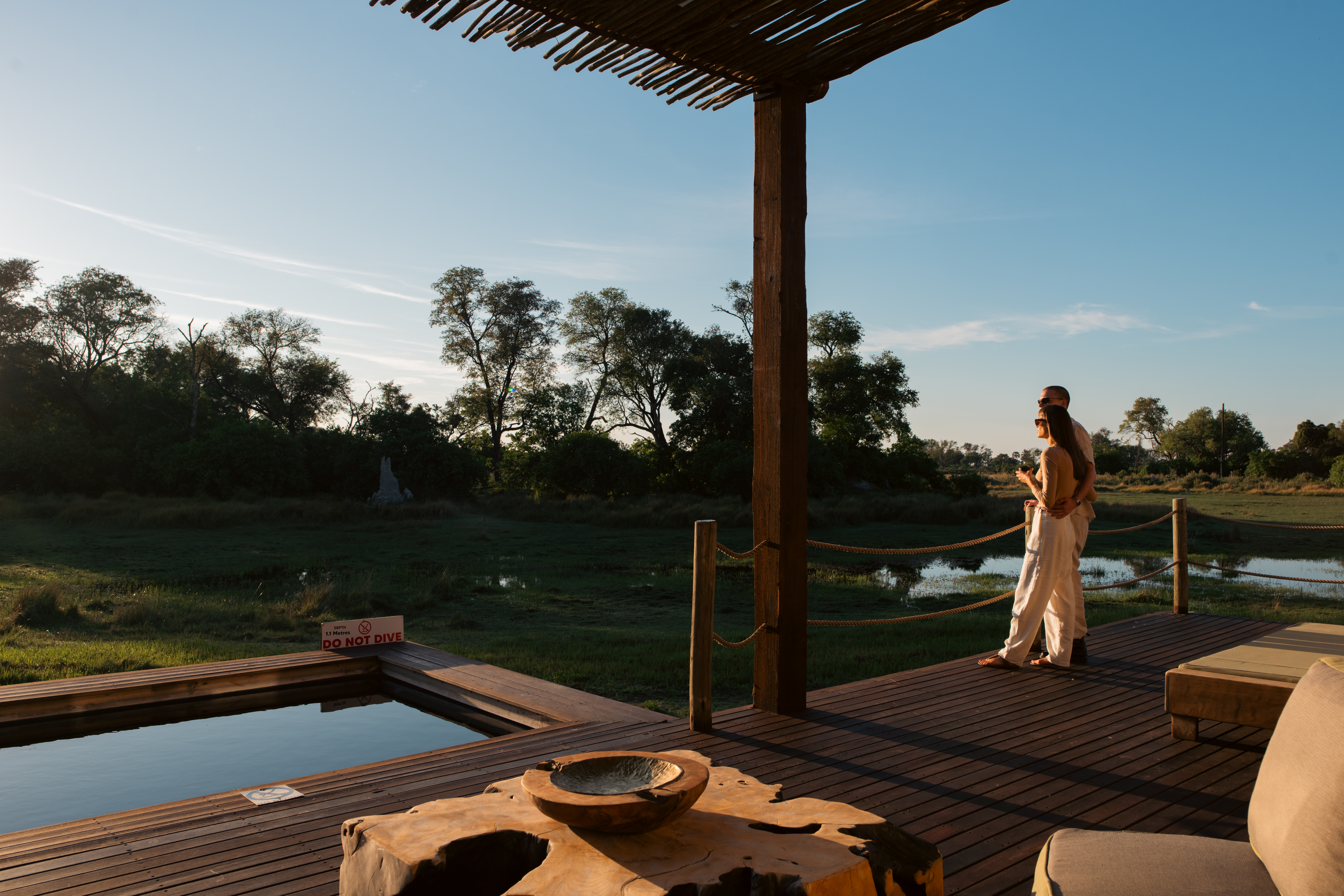 A couple enjoys the sunset in the Okavango Delta from the viewing deck of their suite.