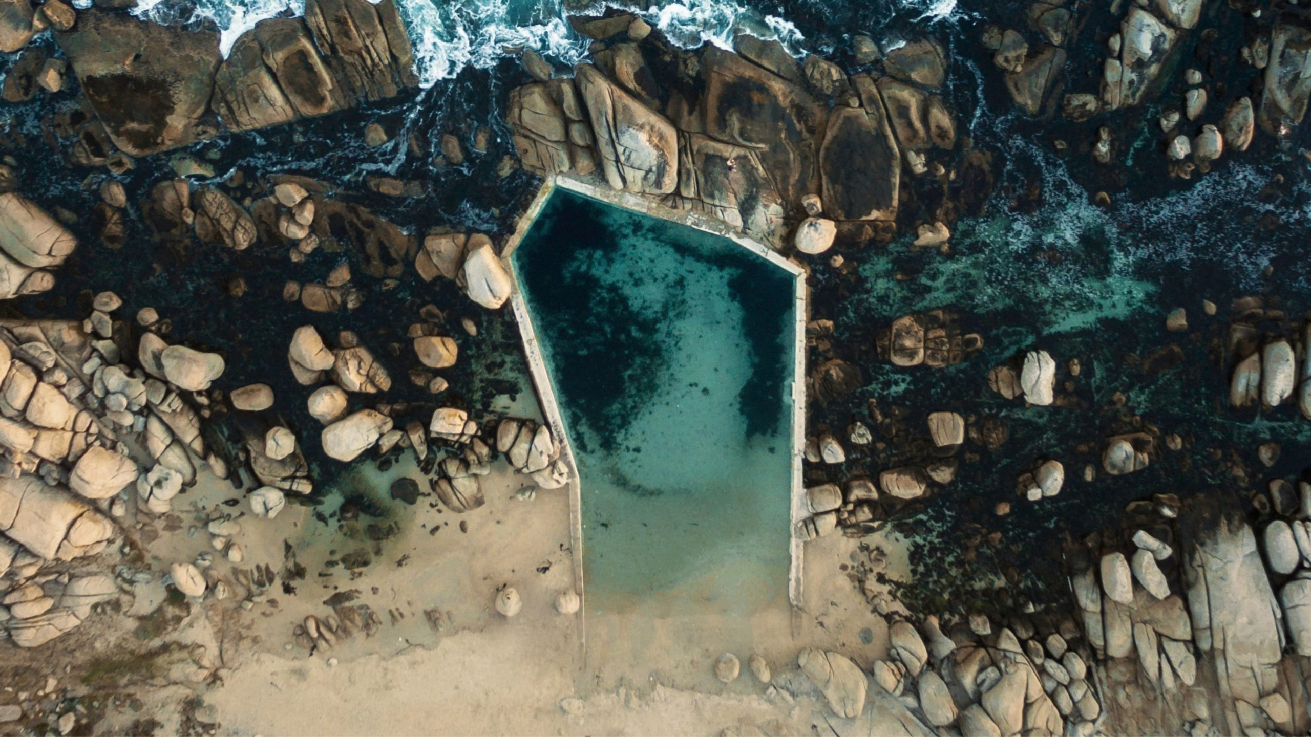 Calm water in the Camps Bay tidal pool, sheltered by rocks at the southern end of the beach