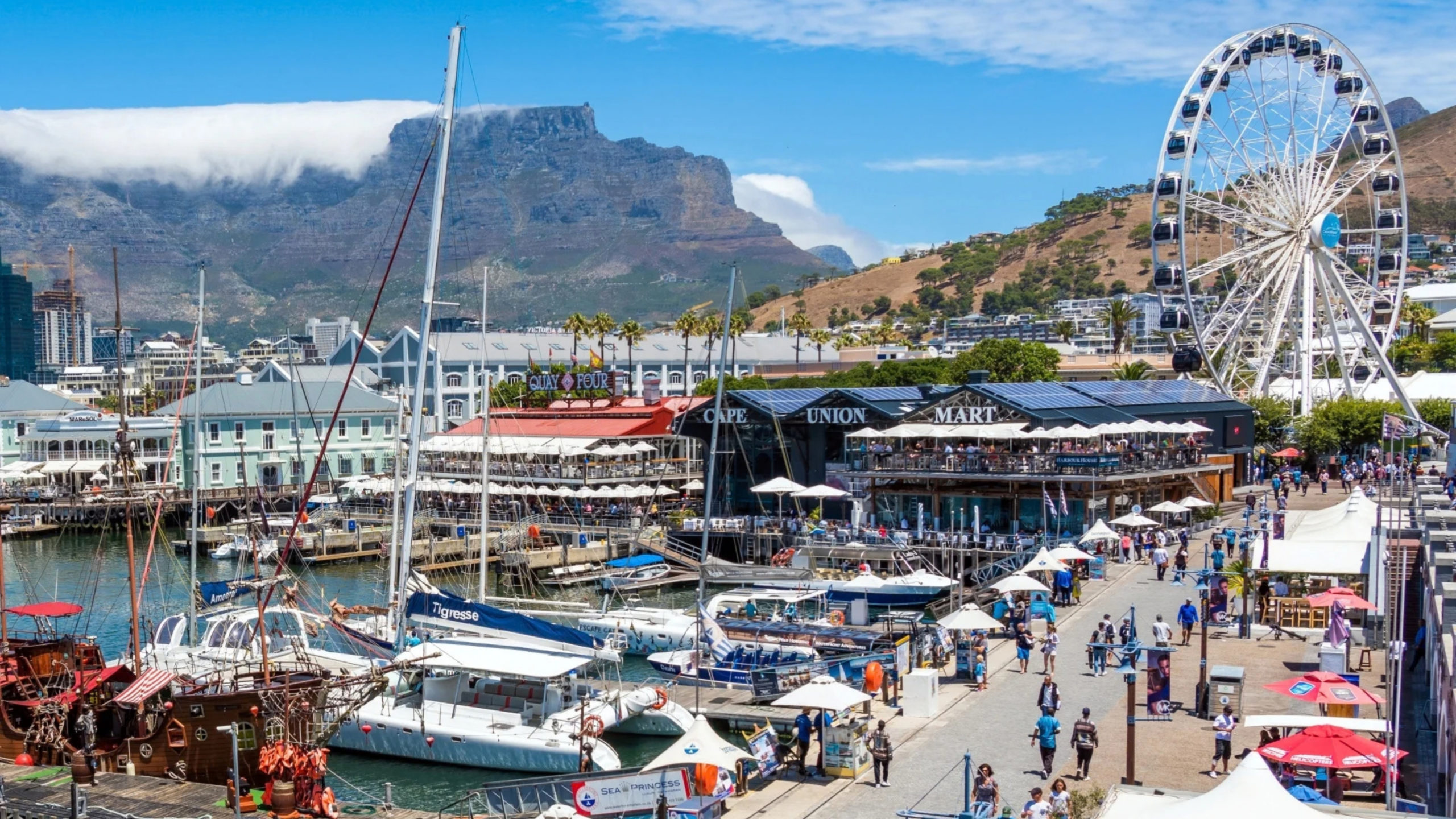 The V&A Waterfront in Cape Town with its Ferris wheel and people strolling along the harbour